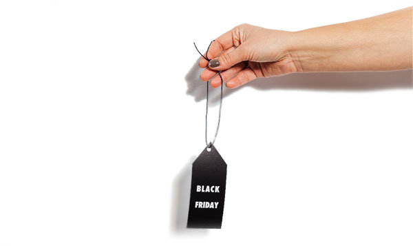 En naken arm som strekker seg ut og holder en svart prislapp med "Black Friday" i tekst på, forann en hvit bakgrunn.
